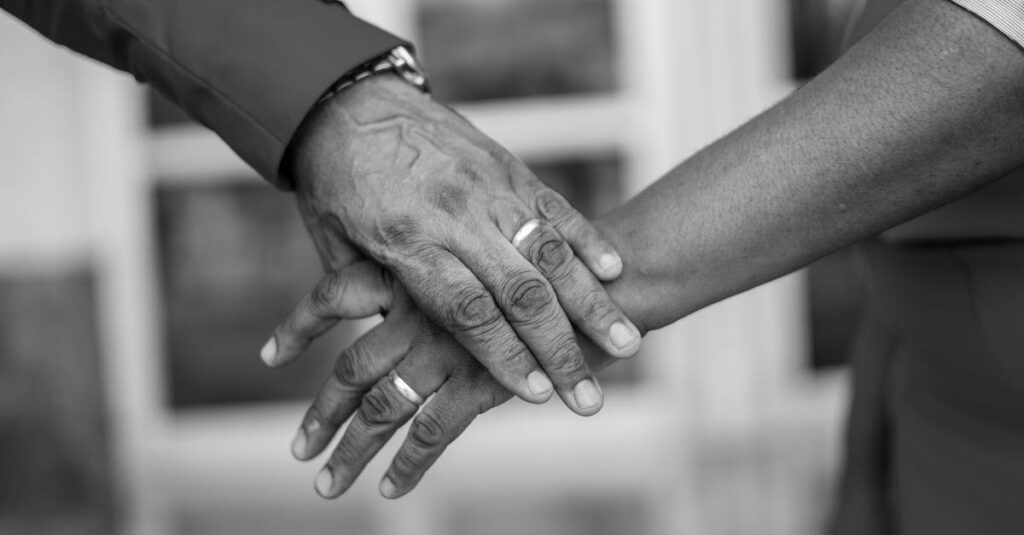A black and white close-up of hands wearing wedding rings, symbolizing love and commitment.